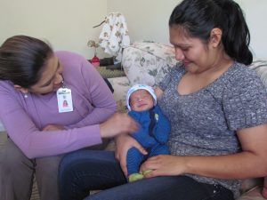 Two adults looking at an infant in the arms of one adult.