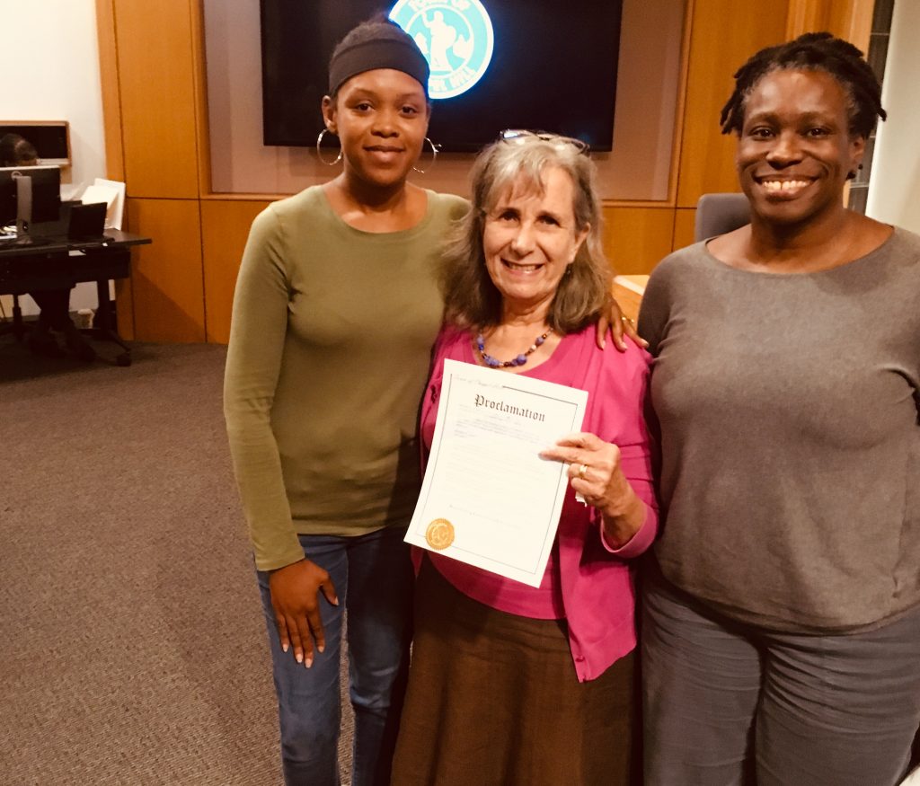 Town Council Member Donna Bell is smiling at the camera with two supporters of breastfeeding family friendly communities, the middle person is holding the proclamation