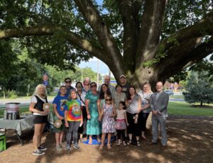 Group photo of people standing in front of a tree