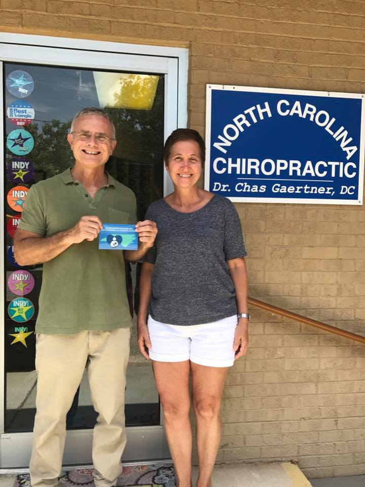NC Chiropractic owner with wife holding a "Breastfeeding Welcome Here" sign in front of the store