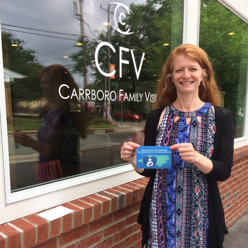 Carrboro Family Vision front window with employee standing in front of window holding breastfeeding communities cling